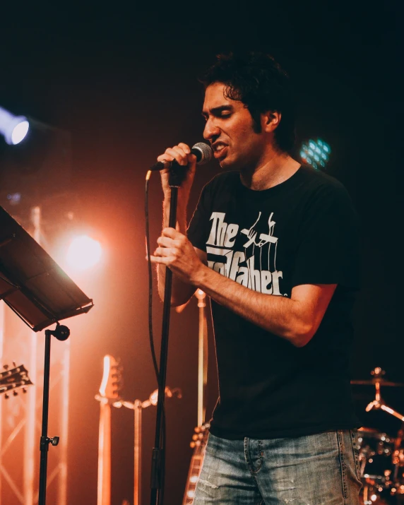 a man holding a microphone in front of his face and a band on stage