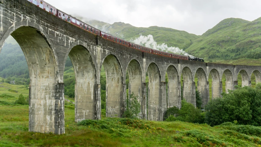 a train traveling across a bridge in the middle of a valley