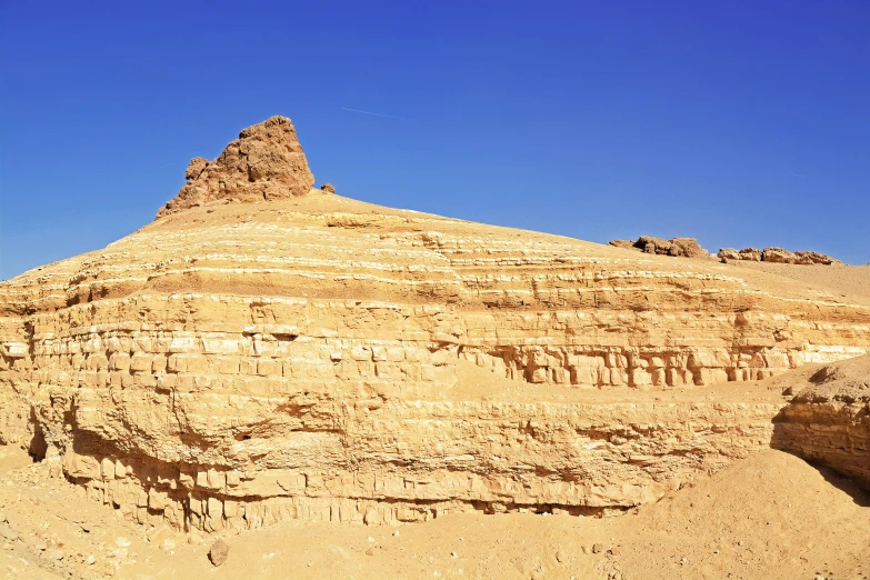 a big dirt mountain with rock face on the top