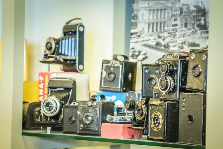 some cameras on a shelf near other old camera