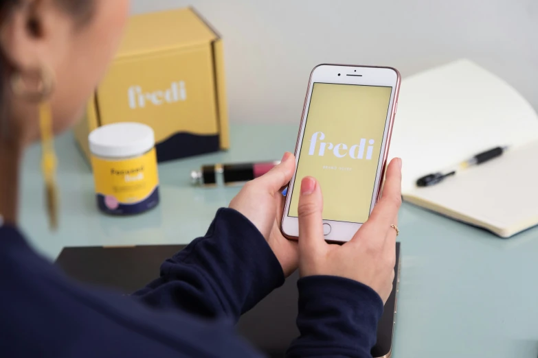 a person holding a phone at a desk with some boxes in the background