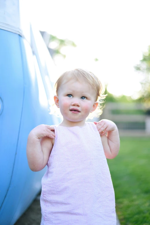 a little girl poses next to a blue truck