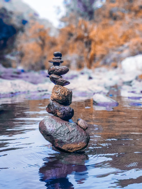 stones stacked together in a lake reflecting the surrounding mountain