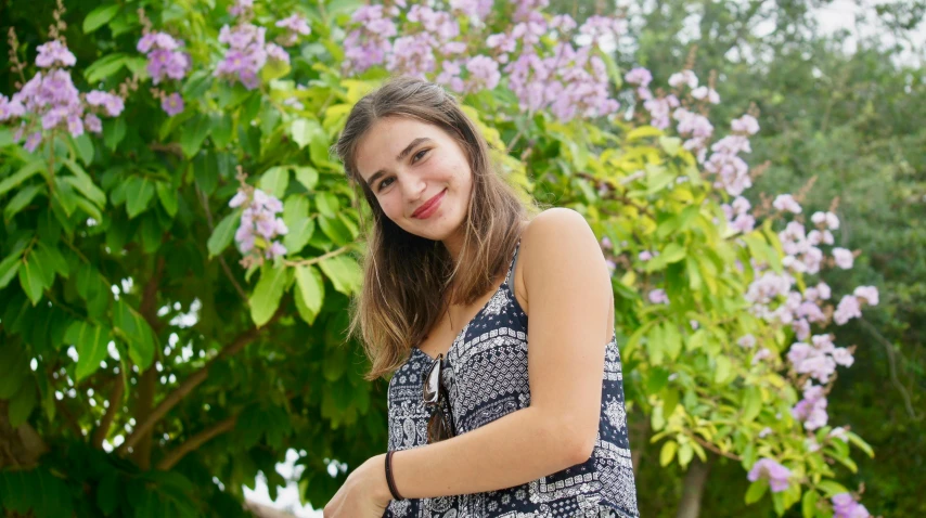 a woman posing for a po in front of lilacs