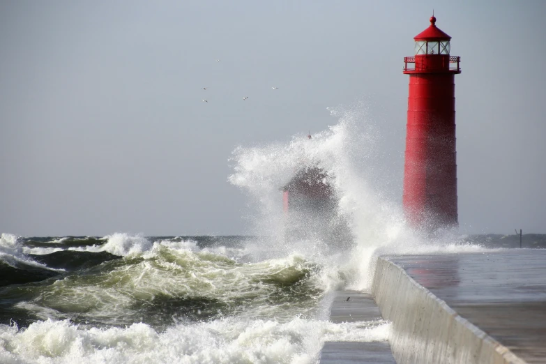 waves crash against a brick wall and lighthouse