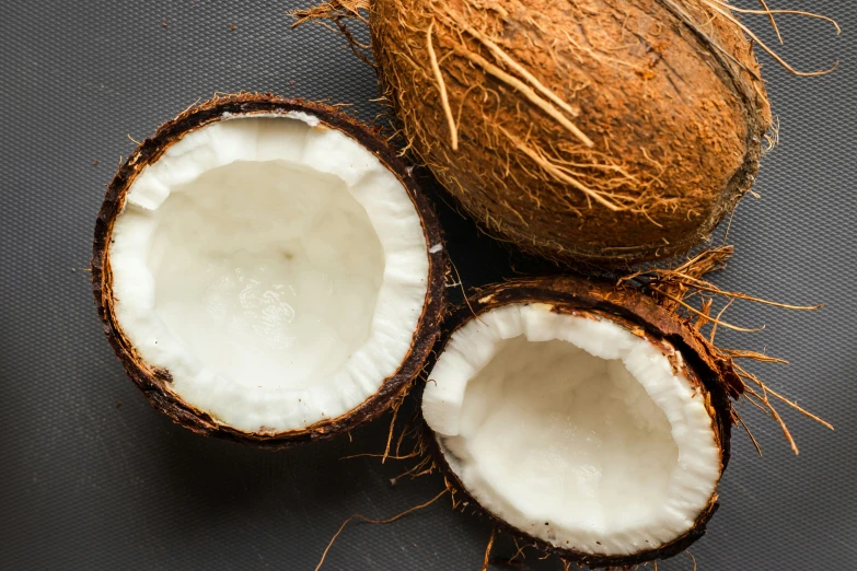 an opened coconut next to the shell on a table