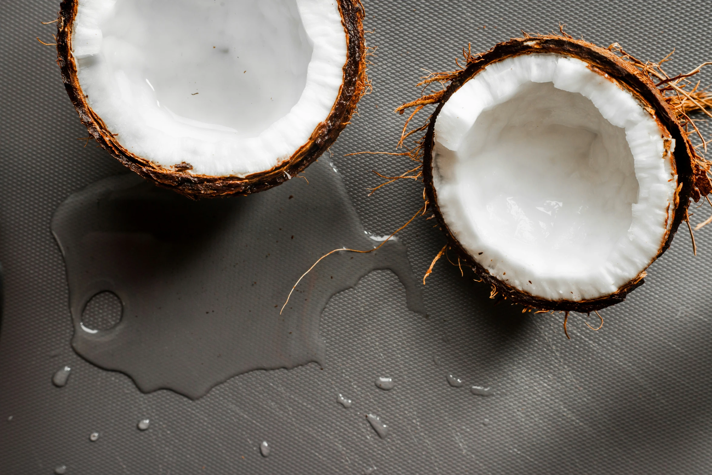 two coconuts on a gray surface one half eaten