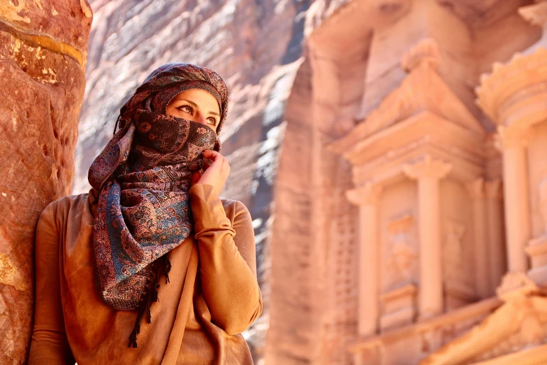 the woman is posing for a po in front of the stone wall