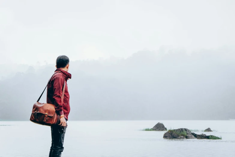 a man with his hands in a brown bag is by the water