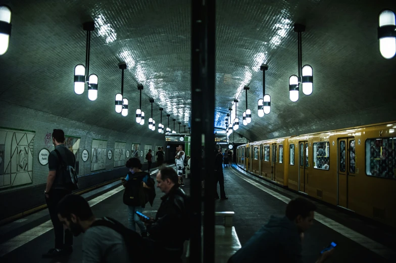 a subway station at night, with people walking on the platform