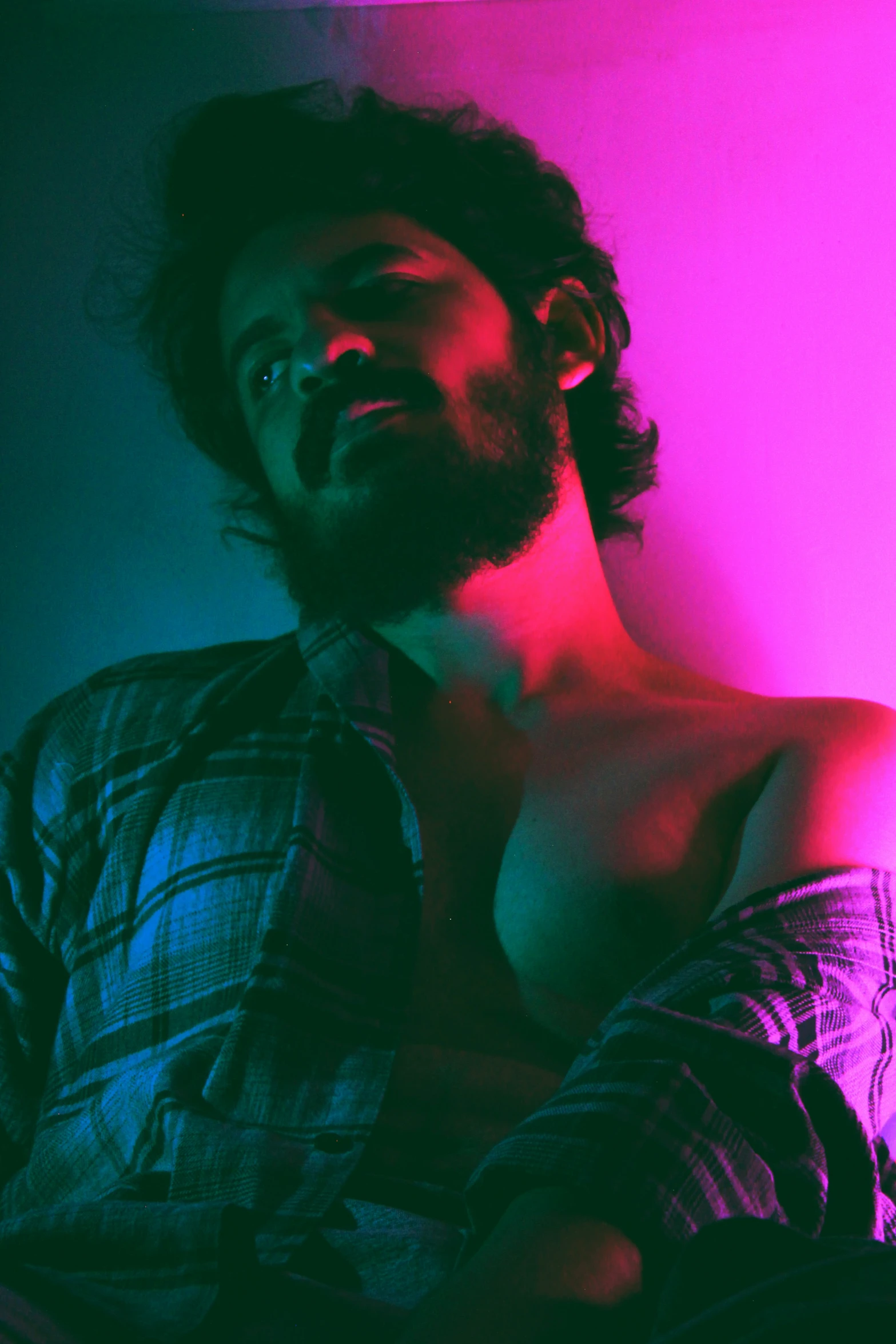 a shirtless man is sitting against a pink light