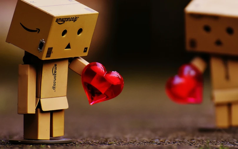 two cardboard people facing each other with red hearts