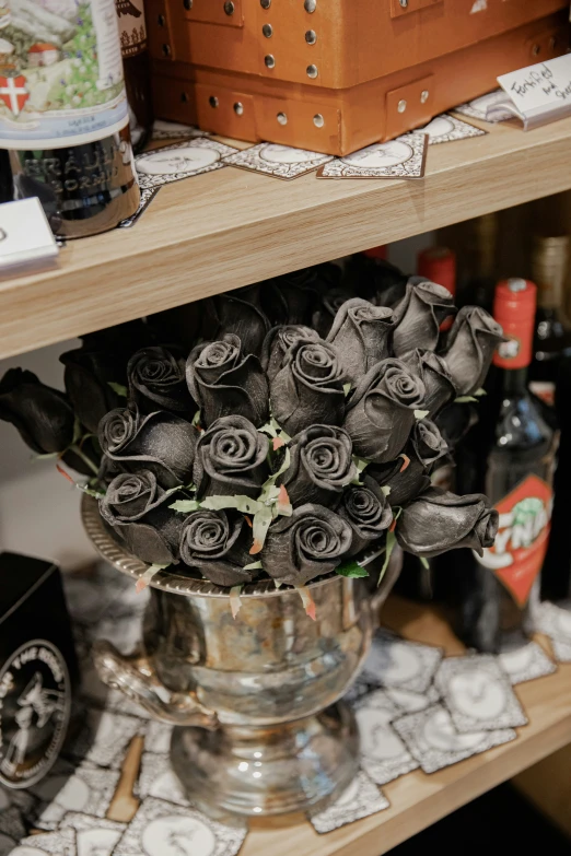 a vase filled with black roses on top of a wooden shelf