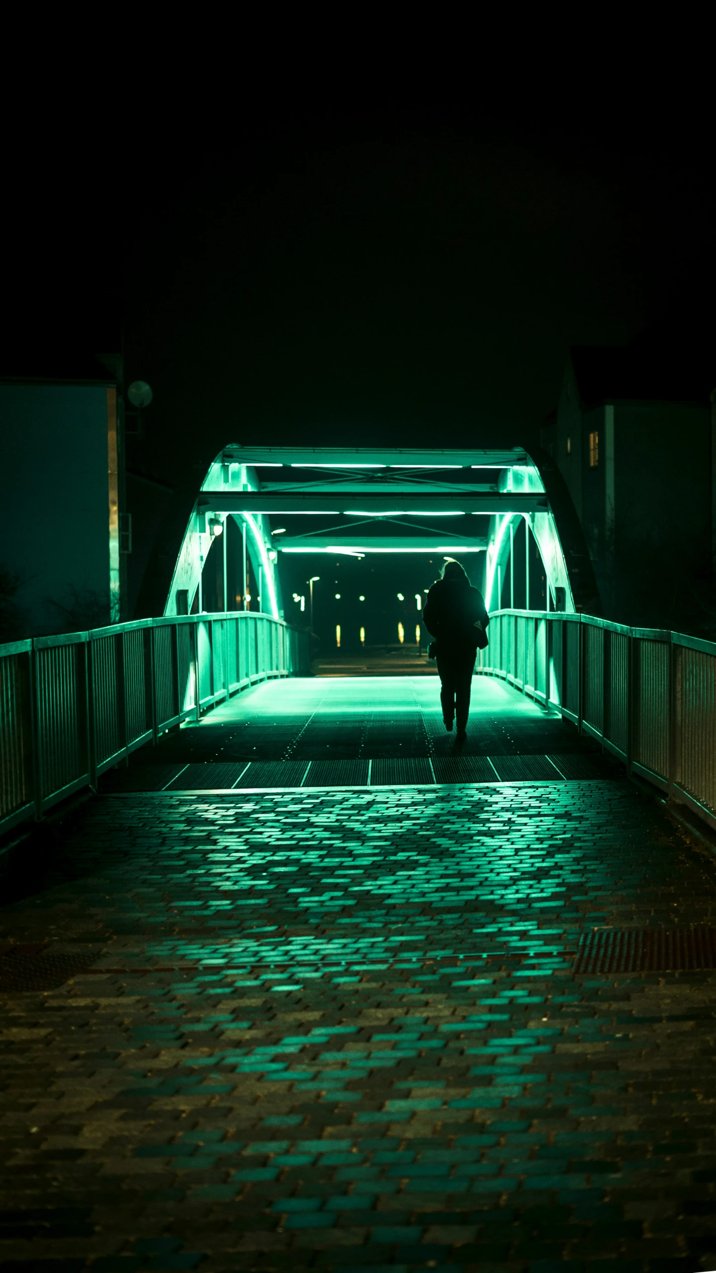 a person walking across a bridge lit up at night