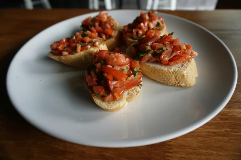 a white plate topped with open faced sandwiches covered in toppings