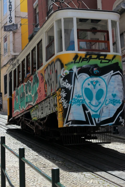 a trolley covered in graffiti is going through a city