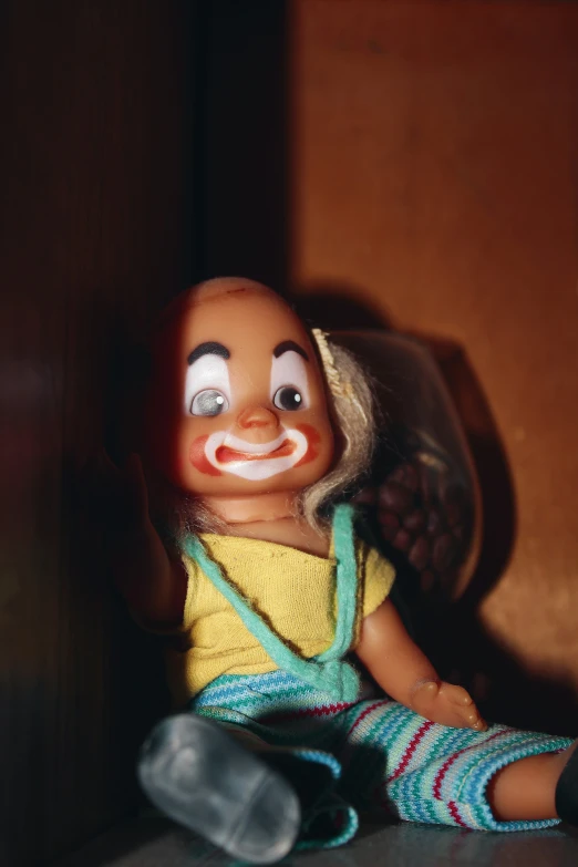 a doll with a clown mask and suspenders on sits down