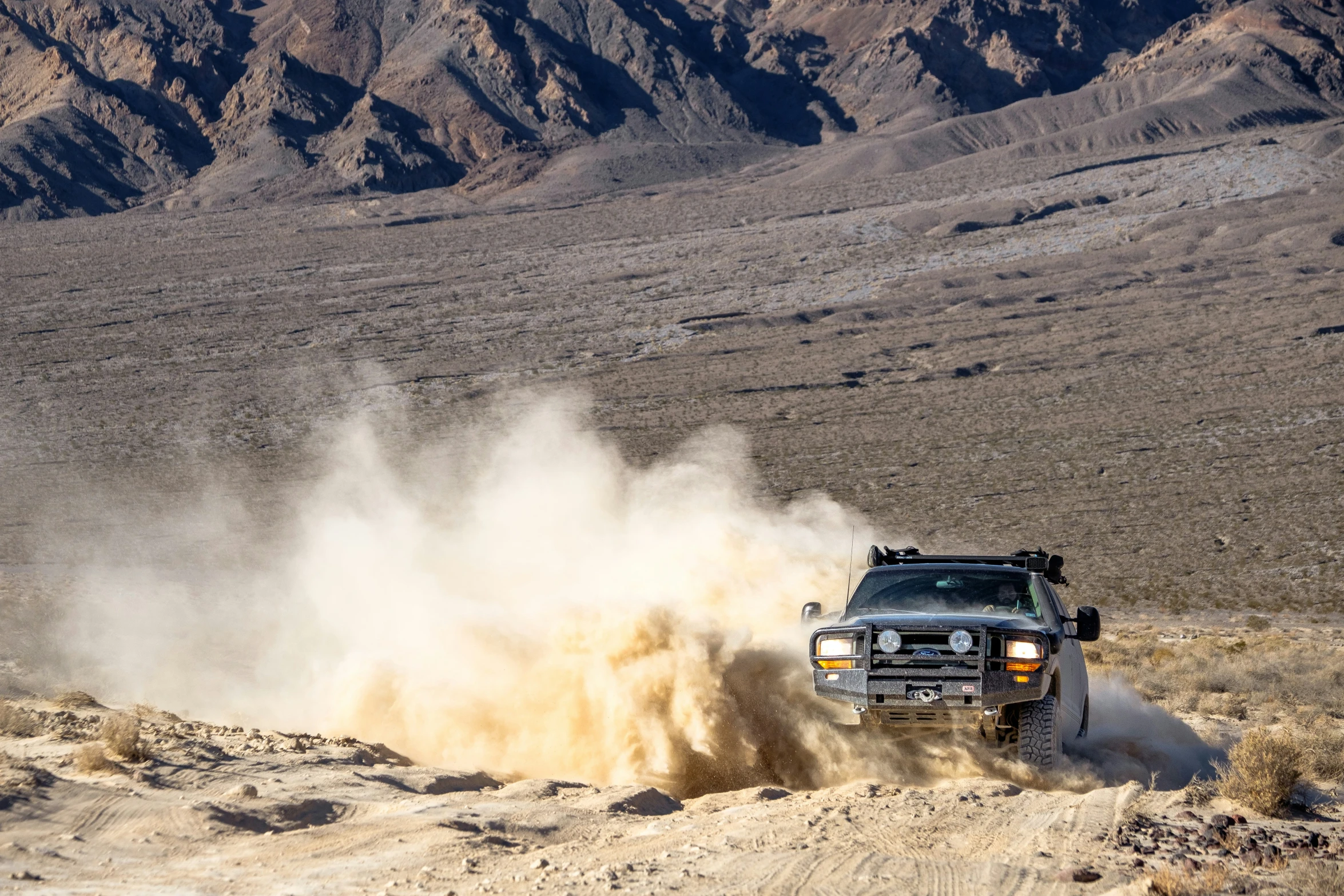 a truck with the front bumper off in desert, in motion