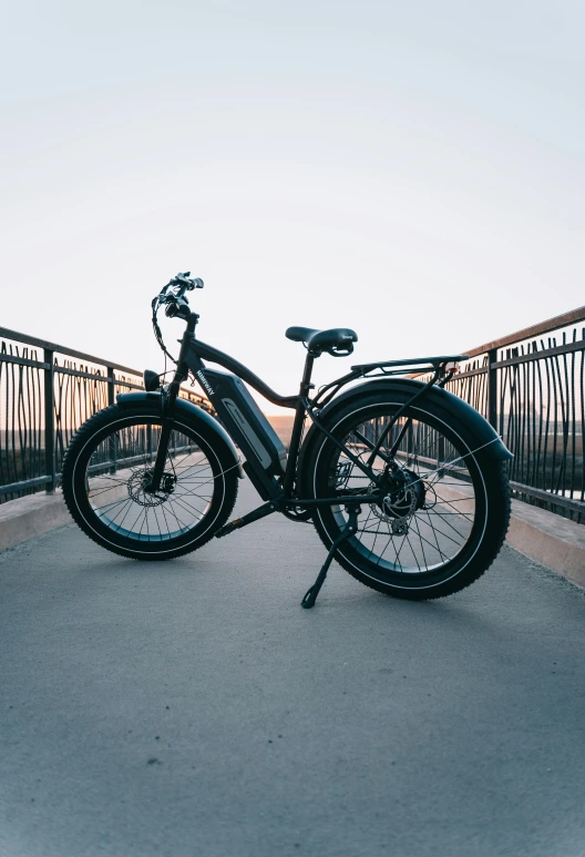 a black bicycle parked by the side of a bridge