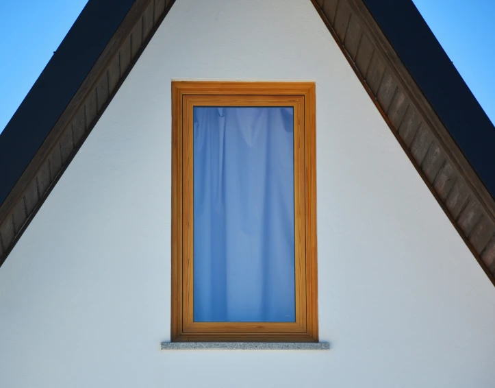 a wooden window in the roof of a white house