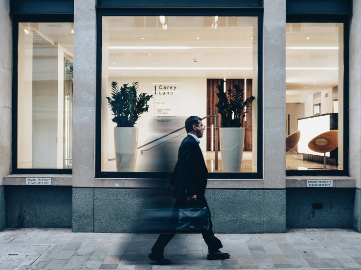 the man is walking by the store windows