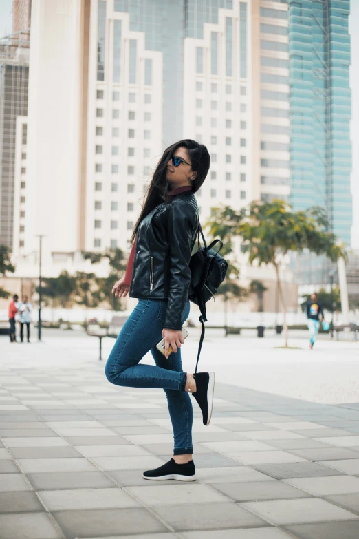 a woman with dark hair and sunglasses wearing blue jeans