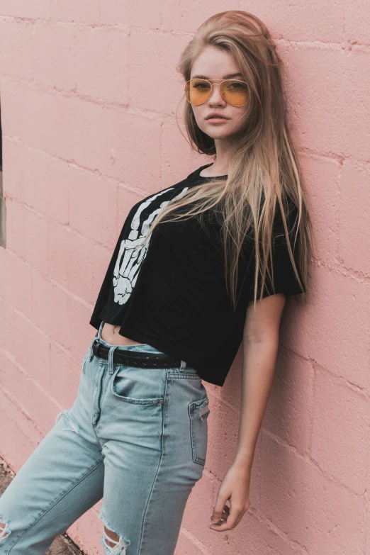 a beautiful young woman standing against a wall