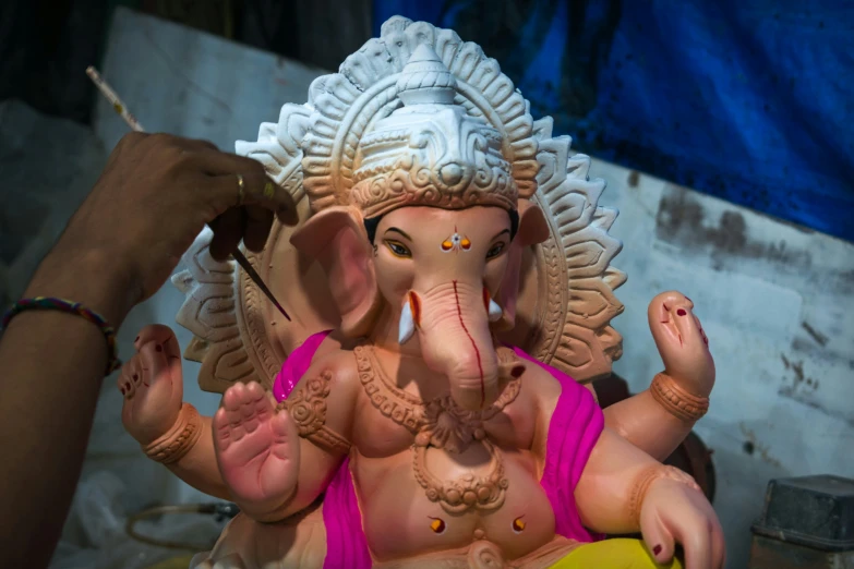 a woman painting an elephant with a paint brush