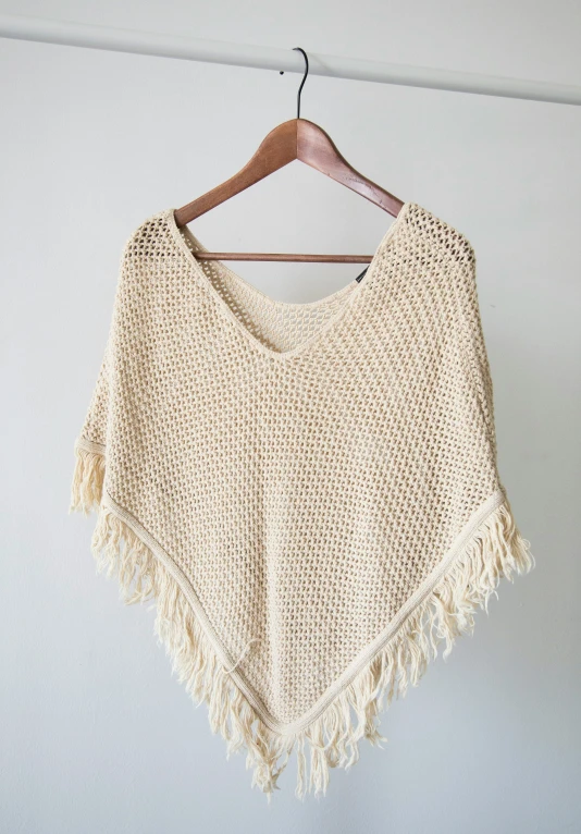 a tan knitted ponchy with long fringe hanging from the back