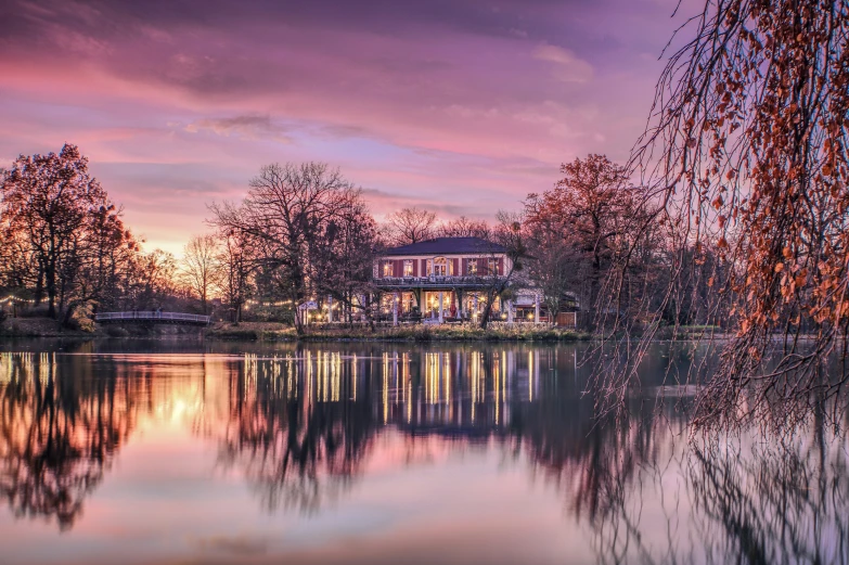 a house on the shore of a lake at sunset