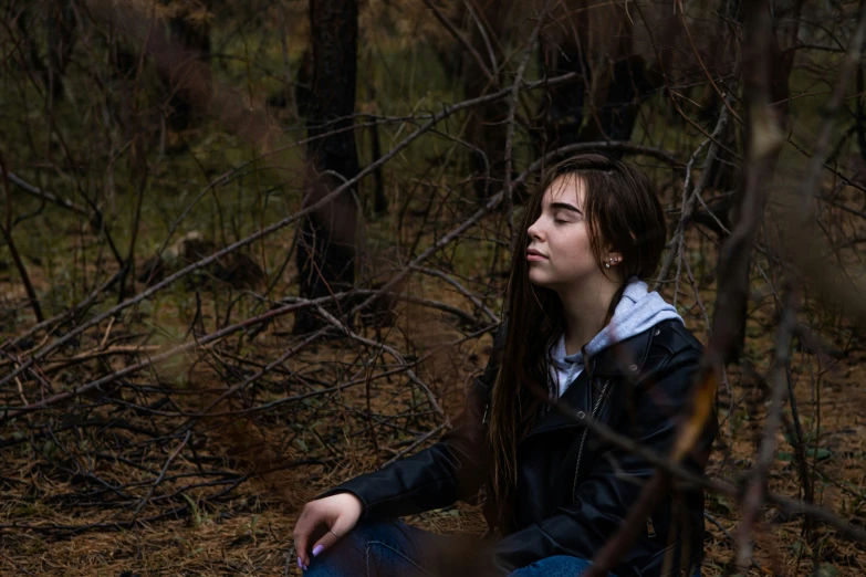 a woman sitting on a wooden bench in the woods