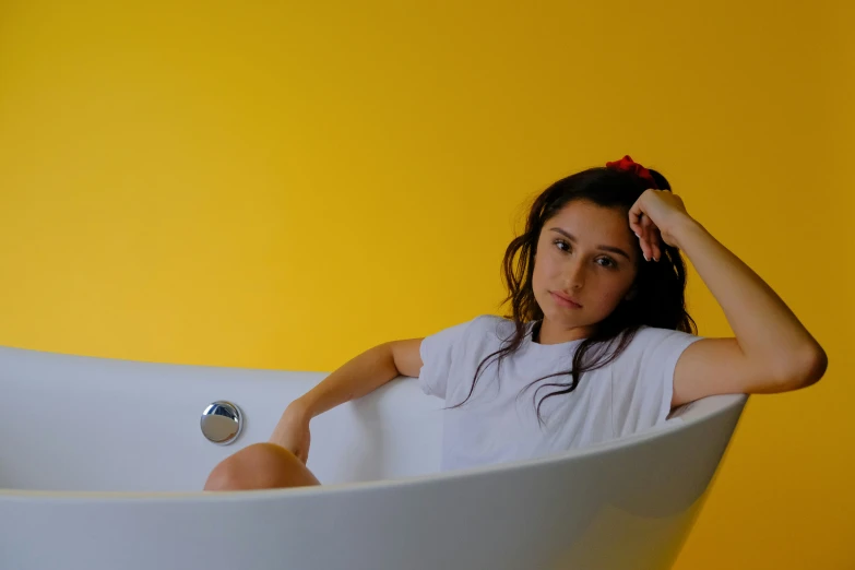 a girl sitting in a white tub wearing a red comb