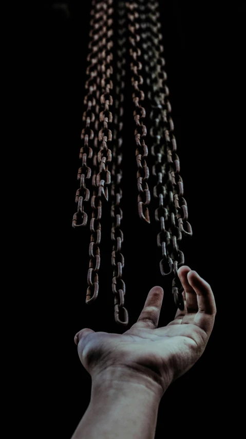 two hands holding chains in the air