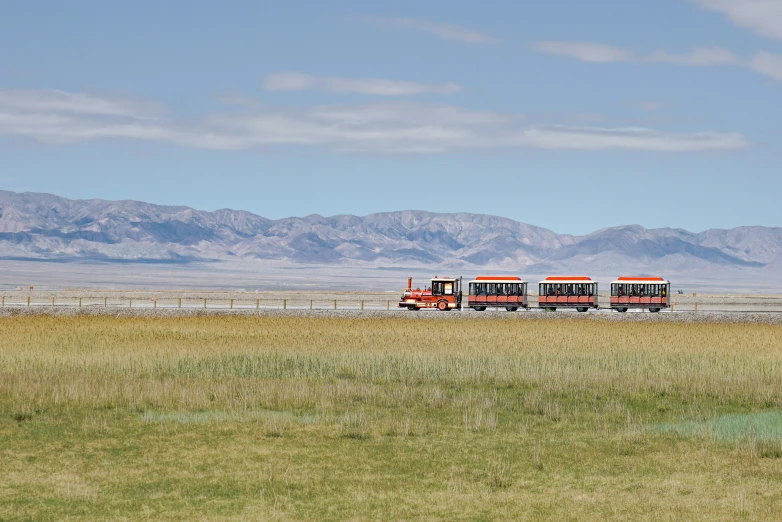 two orange trucks driving in an open field