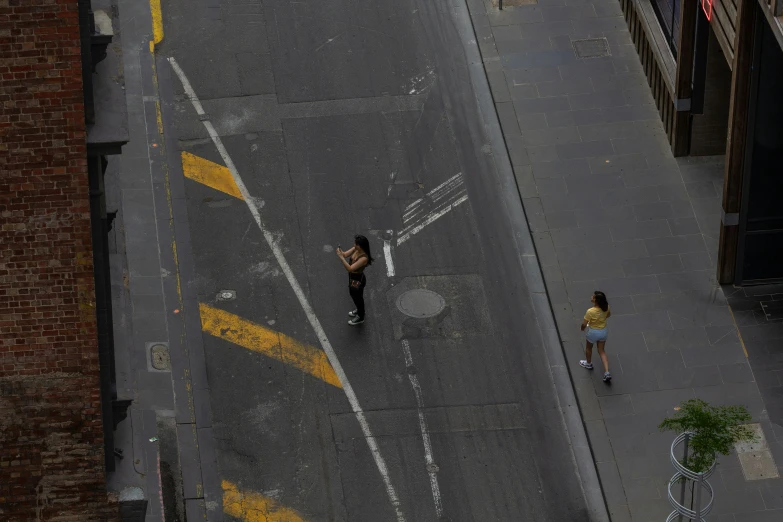 a couple of people walking across a street next to a tall building