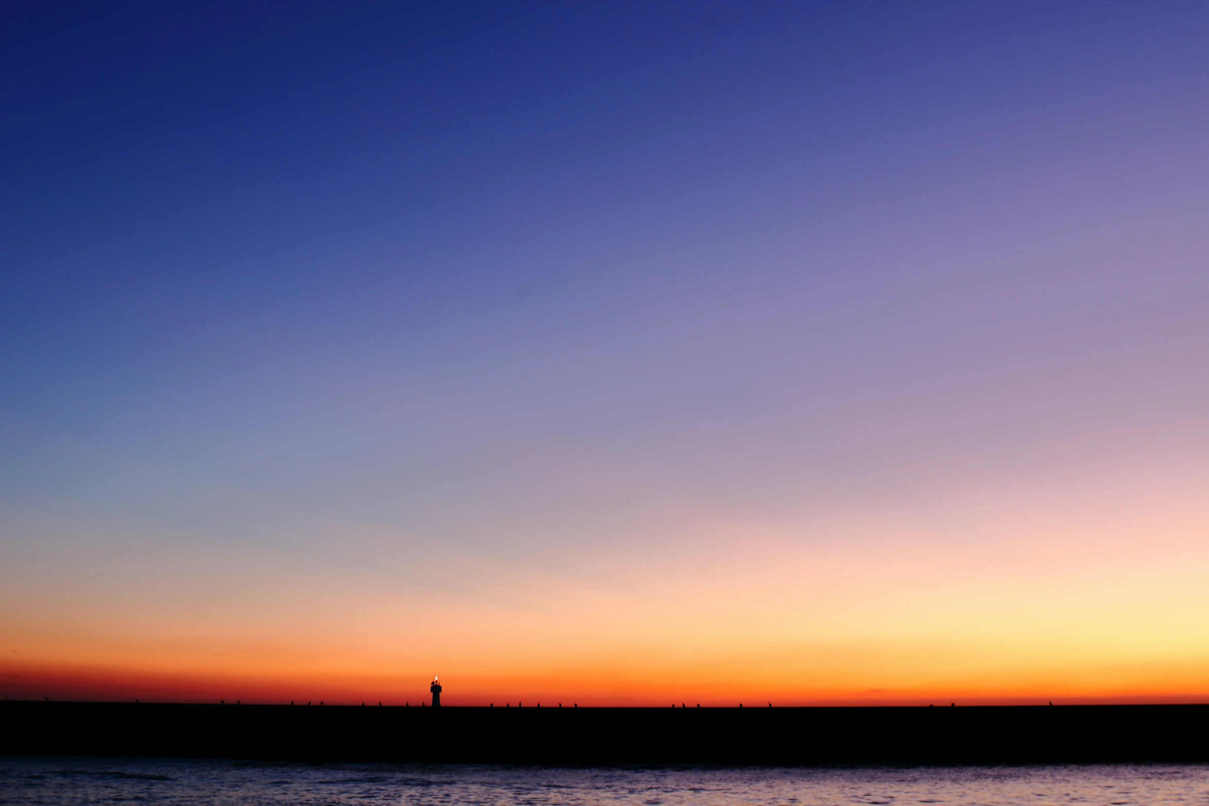 the sunset reflects off the sky at an oceanfront