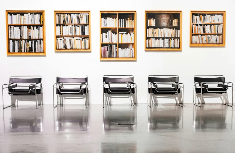 there is an arrangement of empty chairs in a room with bookshelves