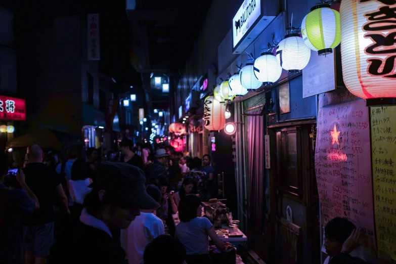 a group of people walking on the side of the street in an alley at night