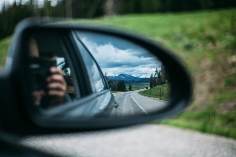 side view mirror reflecting a vehicle on the road