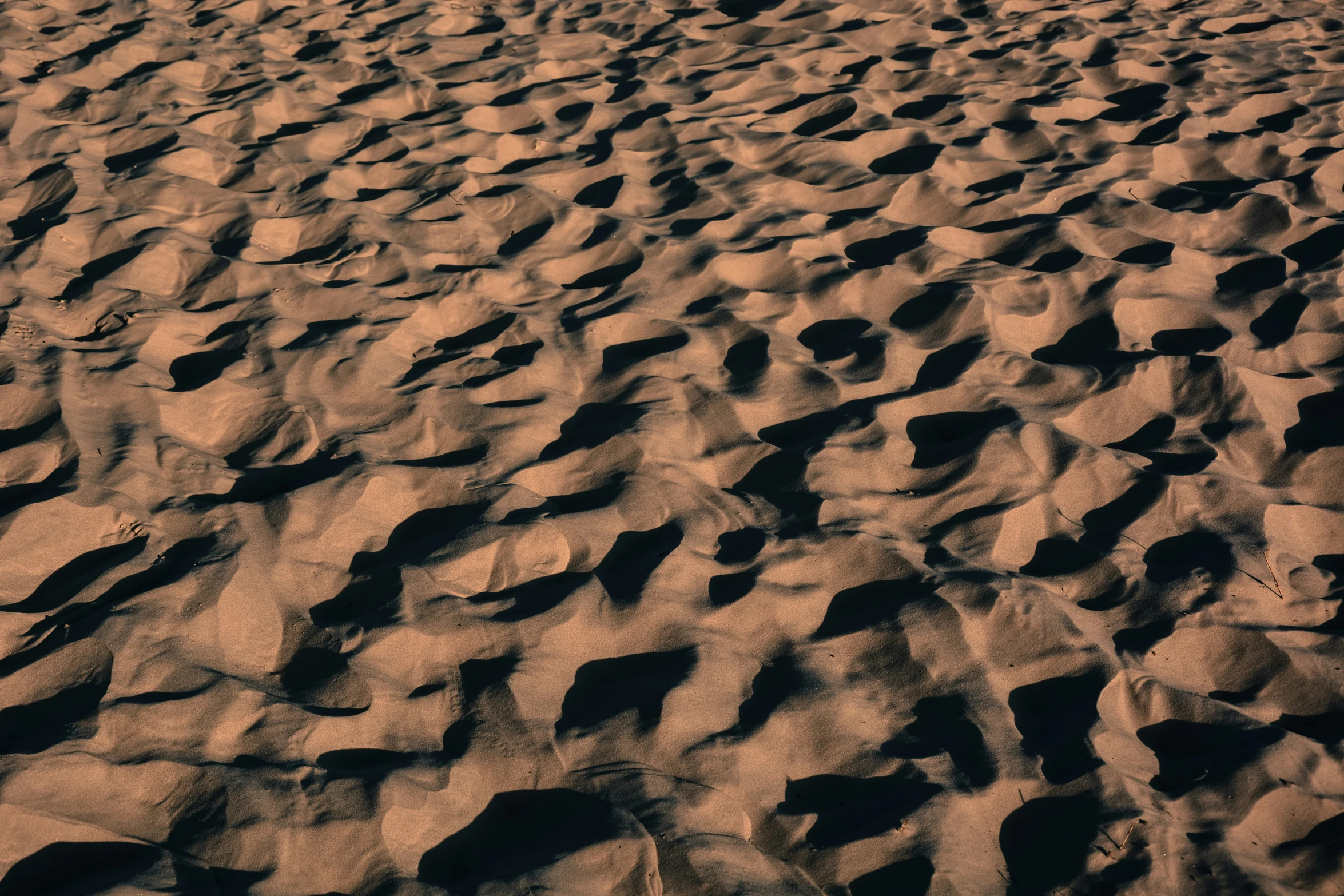 a small plane is flying above a large sand field