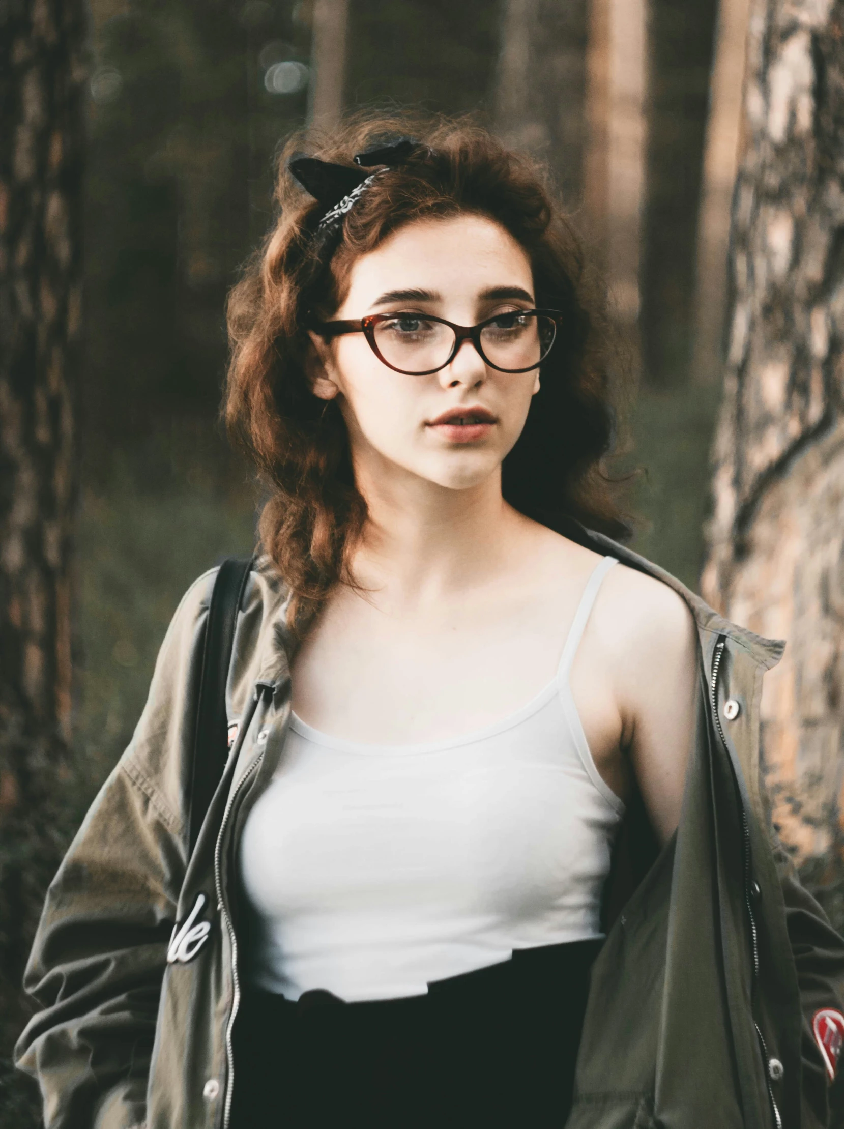 young woman with glasses standing in the forest
