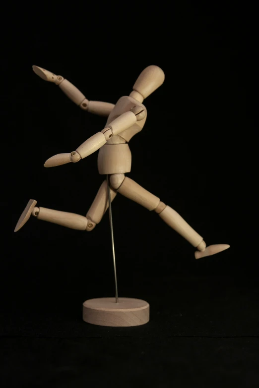 a wooden mannequin figurine on a stand in the dark