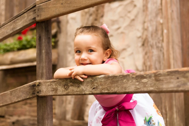 a young child leaning over a wooden fence