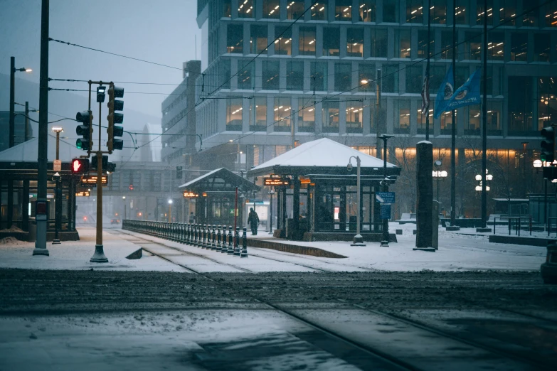 a train station in the snow by a pole and traffic light