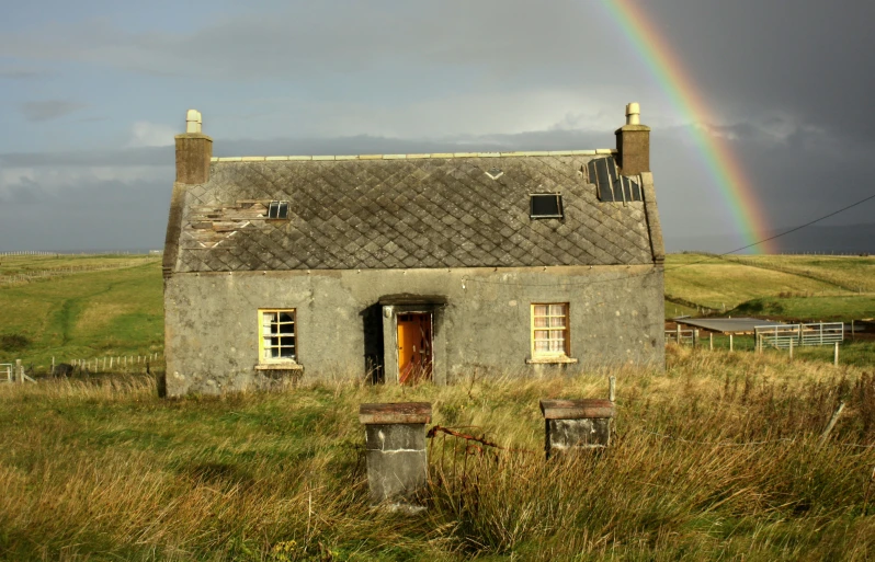 there is a house with a large rainbow in the background