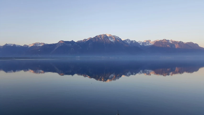 a blue lake with snow covered mountains in the distance