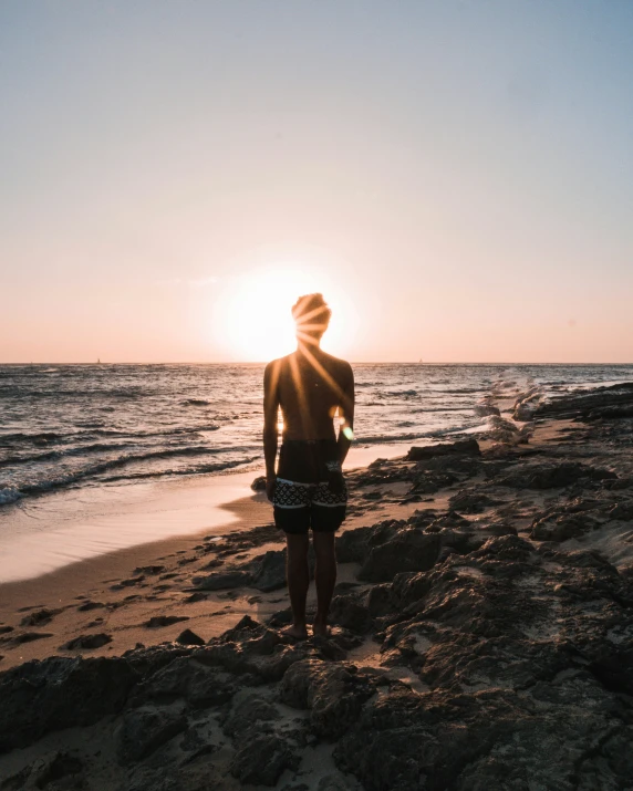 person standing on beach watching the sun rise