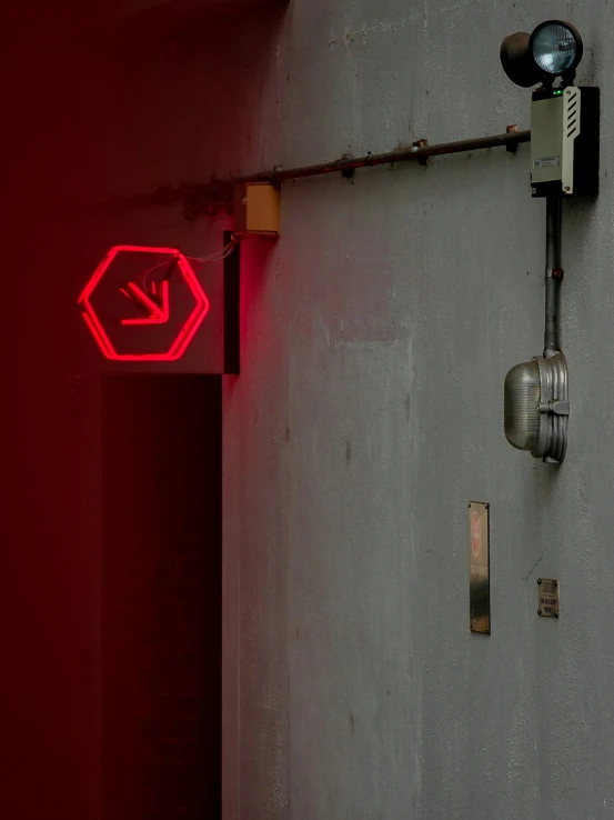 a sign is illuminated on a wall, next to some electrical cords