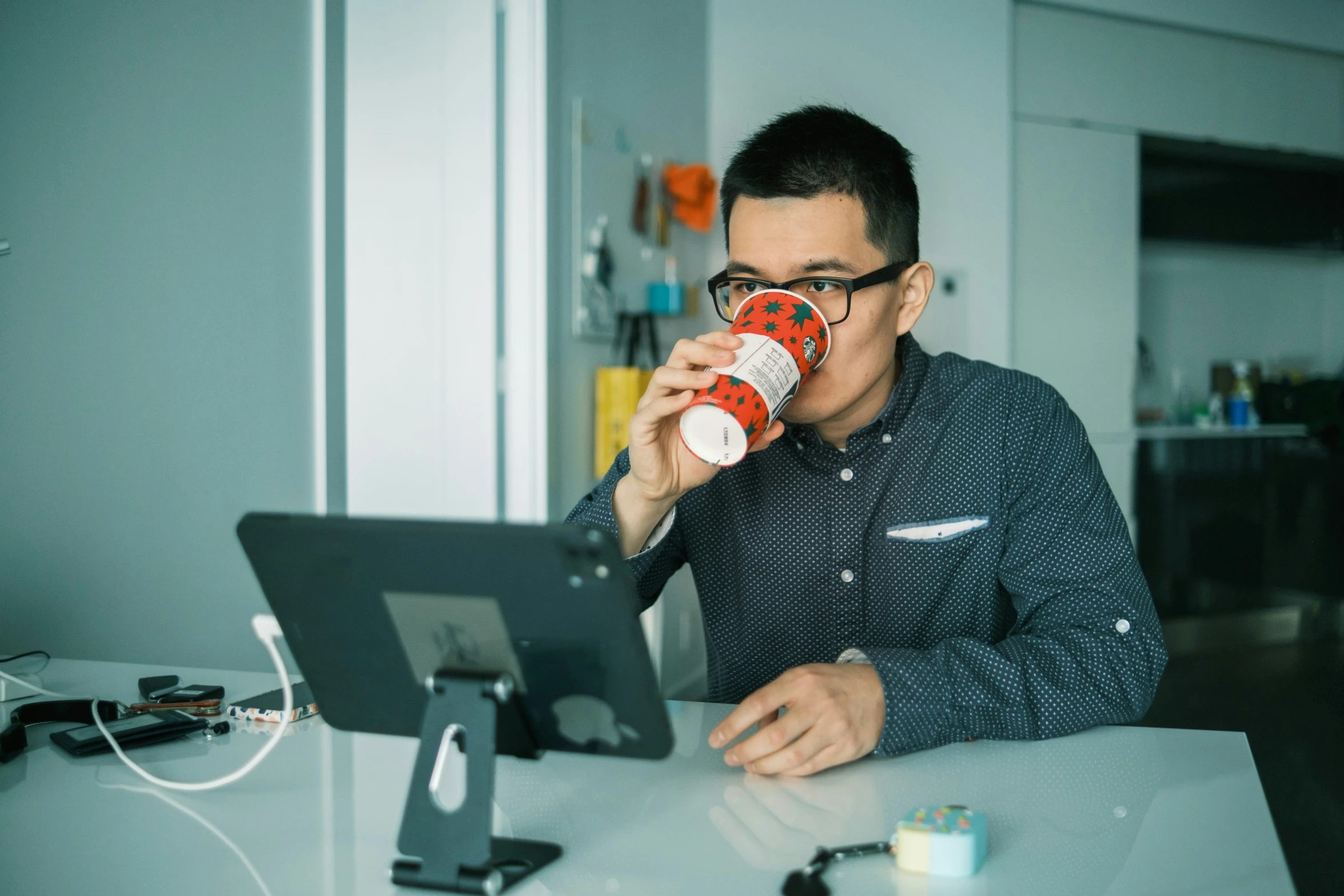 a man drinking a cup of coffee while using his laptop