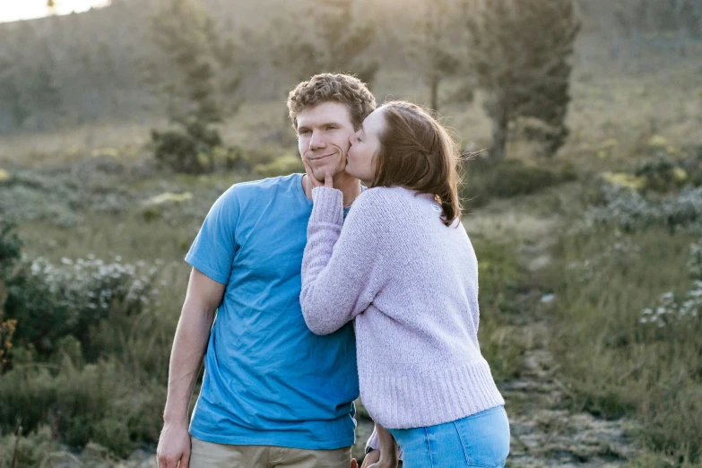 the man and woman are kissing each other while in the field